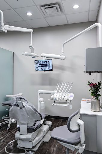 A dental office with a dental chair and a monitor on the wall.
