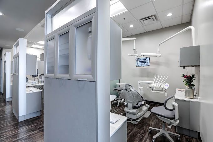 A dental office with a dental chair and a monitor on the wall.
