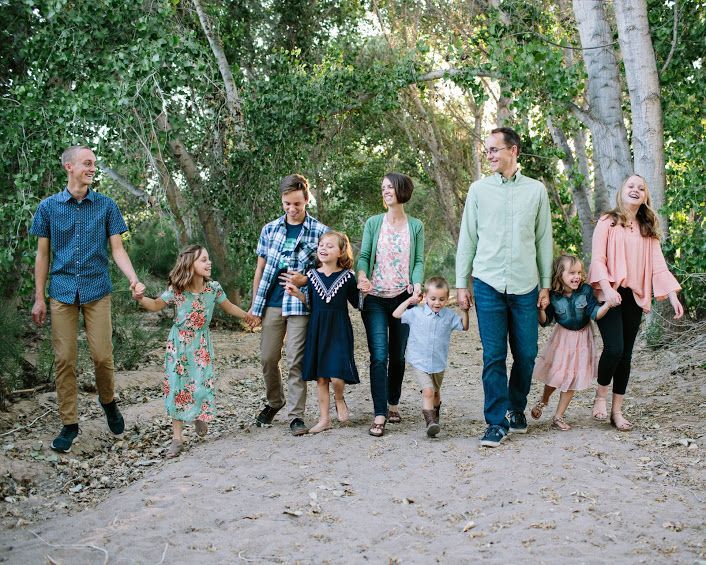 A large family is walking down a dirt path holding hands.