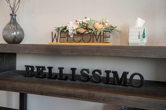 A wooden table with a welcome sign and a sign that says bellissimo on it.