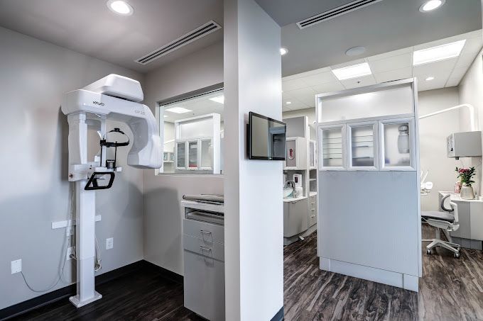 A dental office with a x-ray machine in the middle of the room.