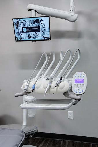 A dental chair with a monitor hanging from the ceiling in a dental office.