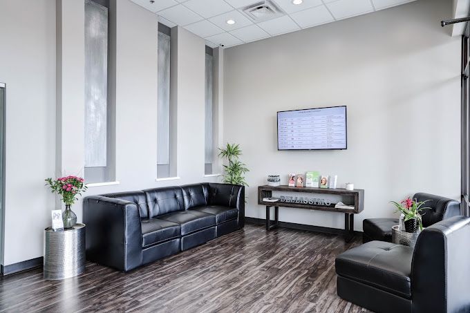 A waiting room with a couch , chairs , and a flat screen tv.