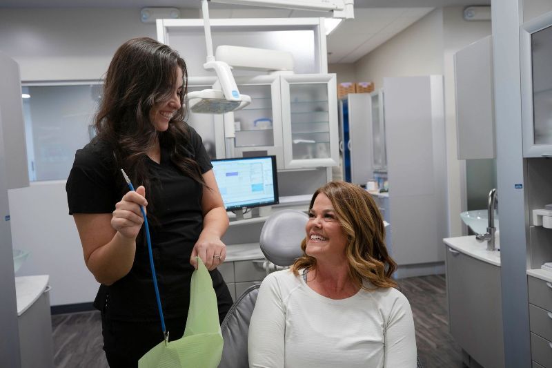 A woman is sitting in a dental chair talking to a dentist.