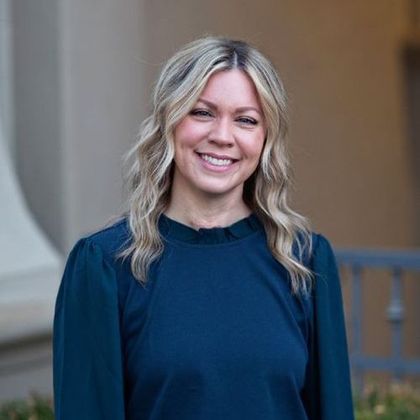 A woman in a blue shirt is smiling for the camera.