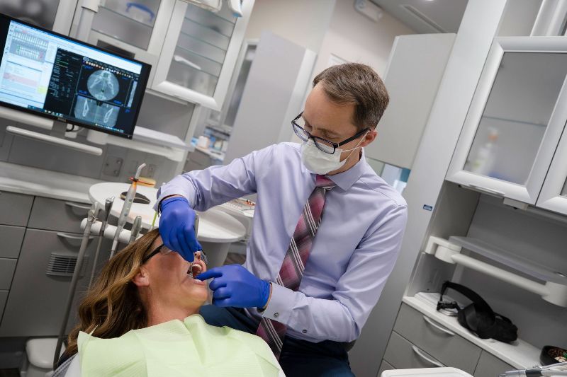 A dentist is examining a woman 's teeth in a dental office.