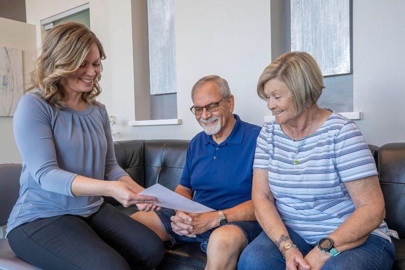 A woman is sitting on a couch talking to a man and woman.