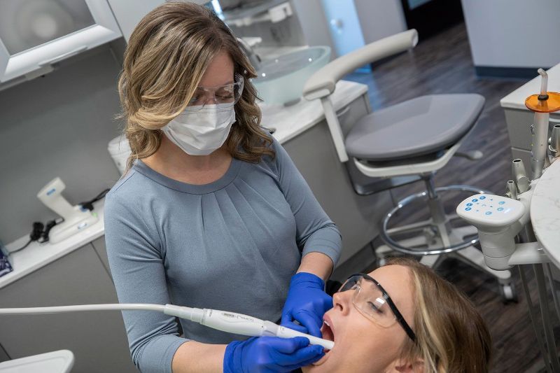 A woman is getting her teeth examined by a dentist in a dental office.