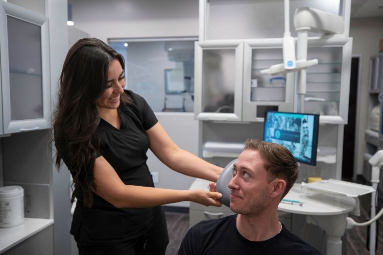 A woman is examining a man 's face in a dental office.