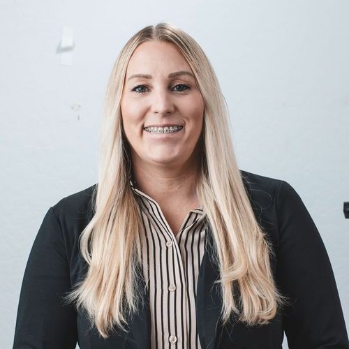 A woman wearing braces and a striped shirt is smiling for the camera.