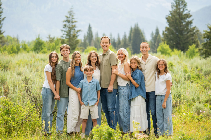A large family is walking down a dirt path holding hands.