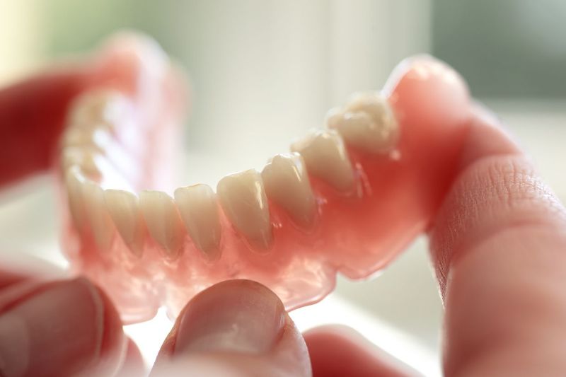 A person is holding a denture in their hands.