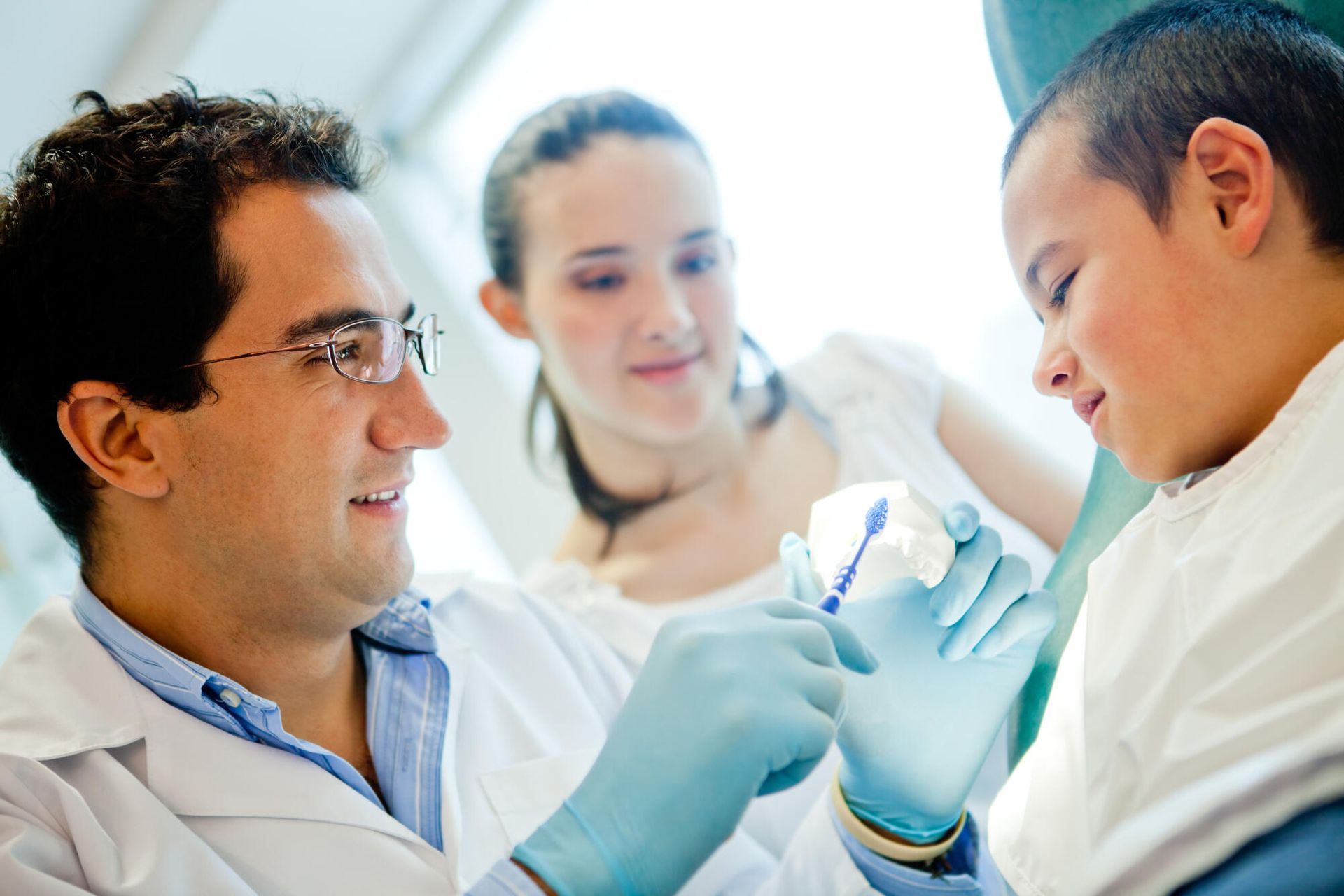 A dentist examines a child 's teeth in a dental office