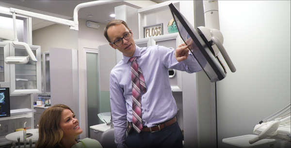 A dentist is talking to a patient in a dental office.
