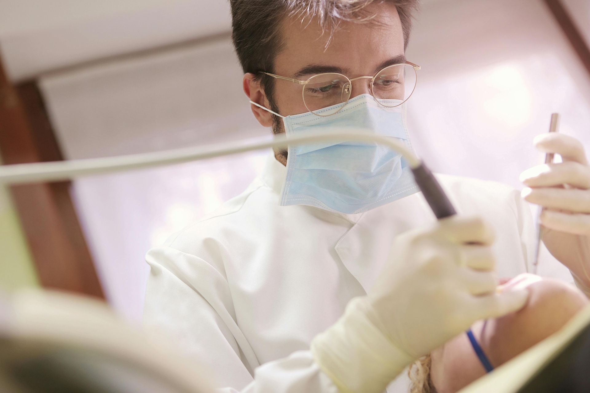 A woman is examining a man 's teeth in a dental office.