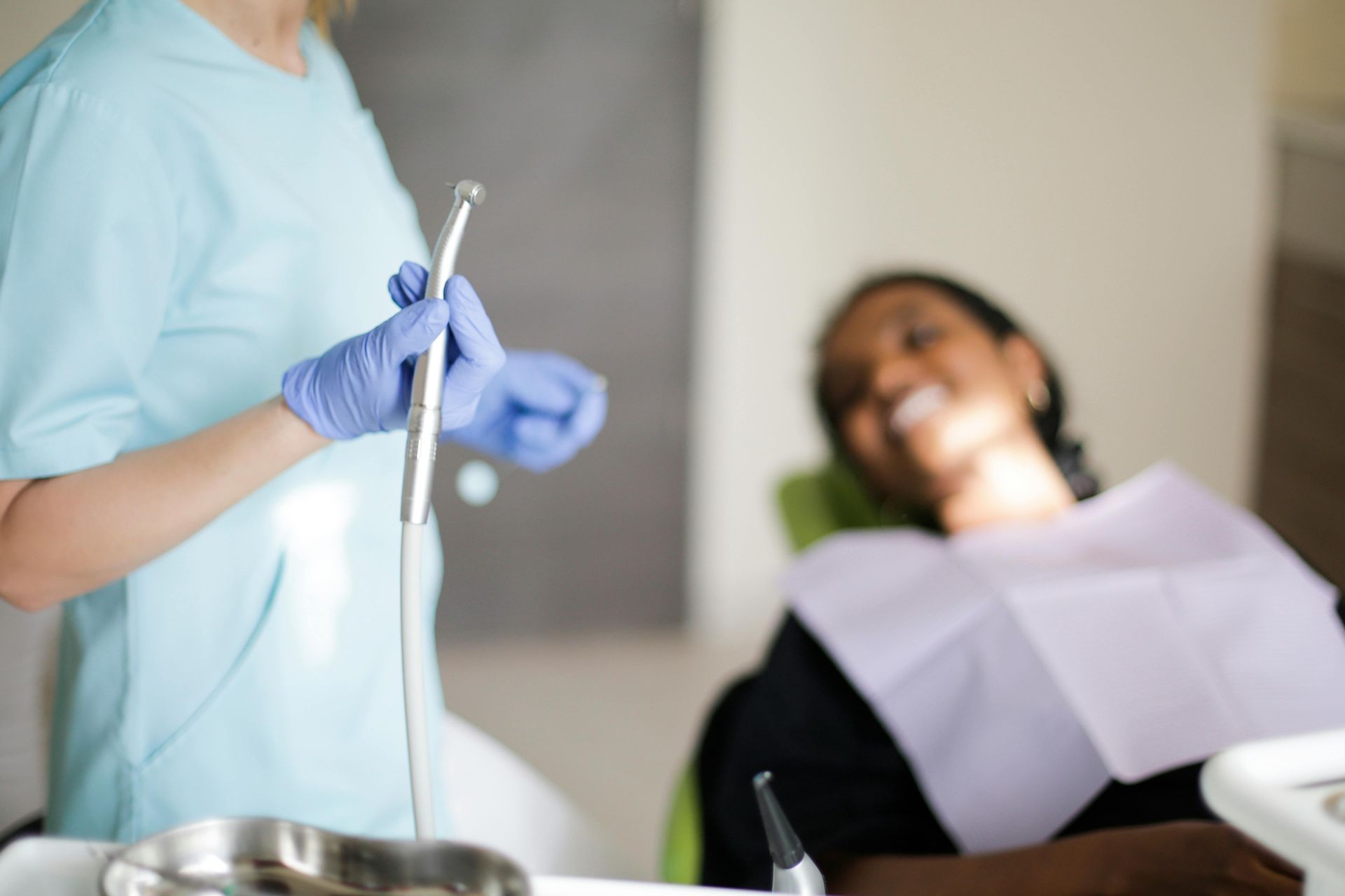 A woman is examining a man 's teeth in a dental office.