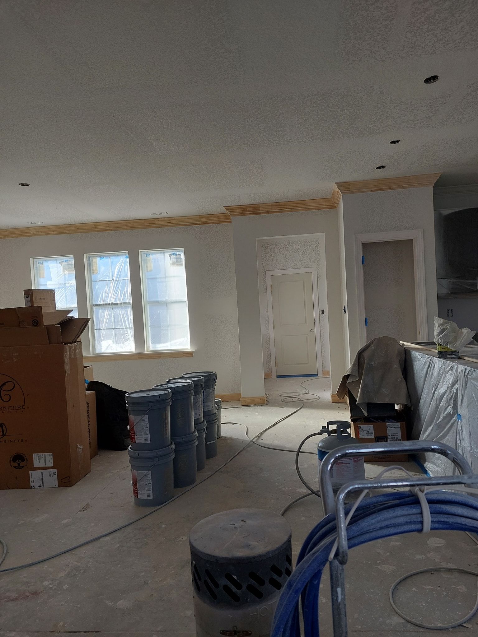 Renovation room with boxes, tools, coiled hoses, and unfinished walls and ceiling