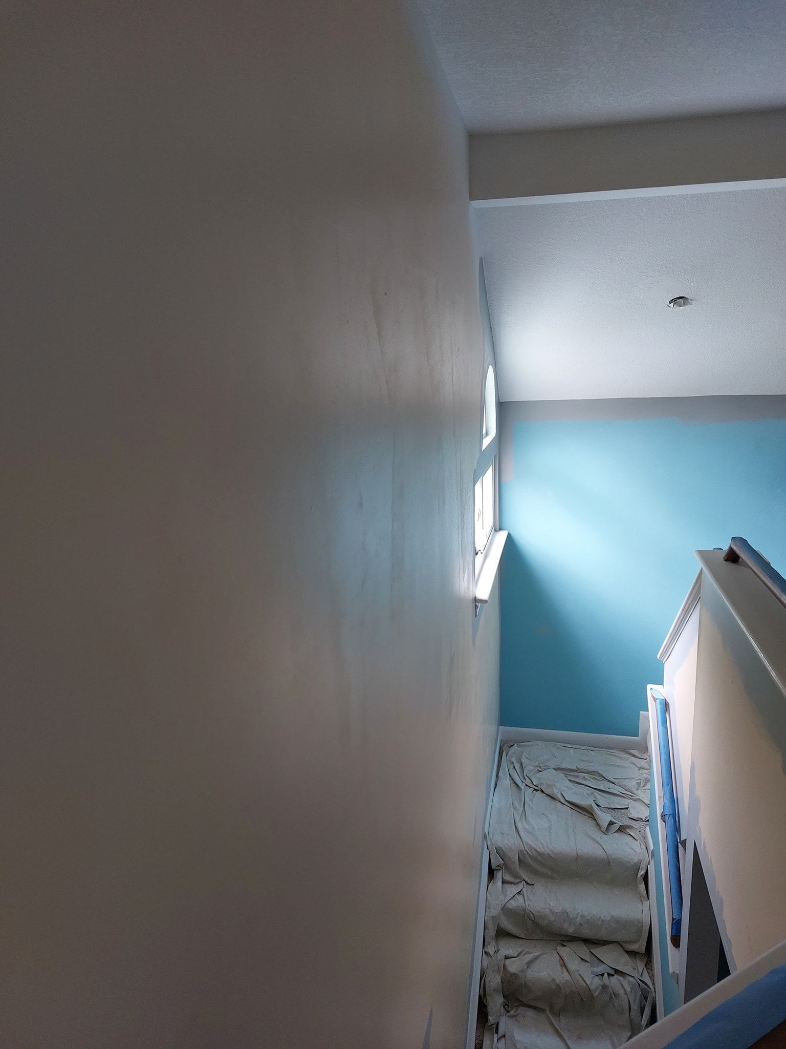 Narrow stairwell with blue walls, white ceiling, and carpeted stairs leading upward.