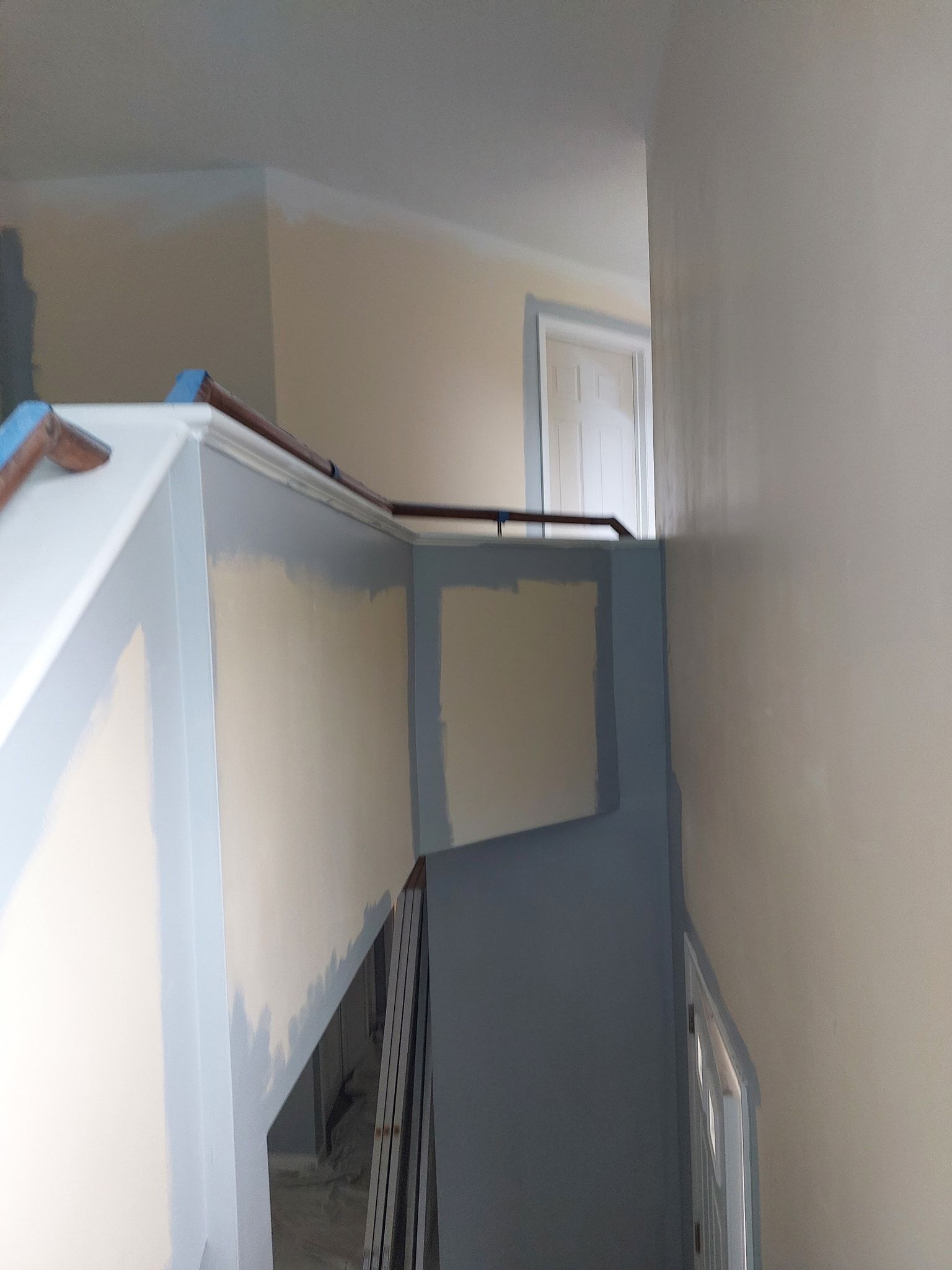 Narrow indoor stairwell with blue walls, white trim, and a small window at the top.