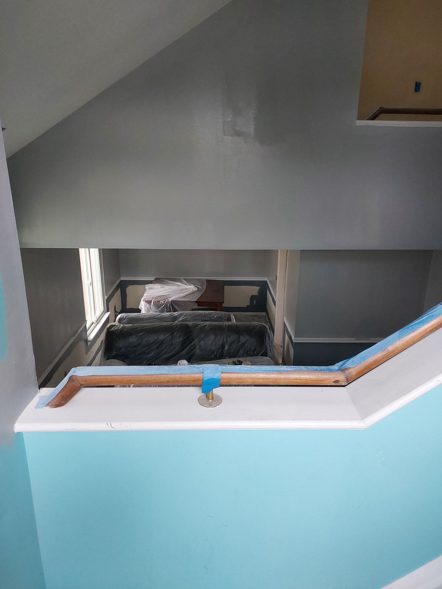 Stairwell with light blue half-wall, white railing, and a landing overlooking a lower floor.