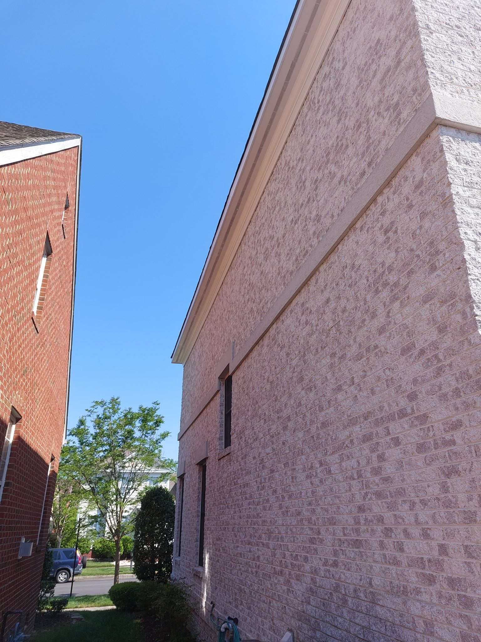 Narrow alley between brick and stucco buildings under a clear blue sky