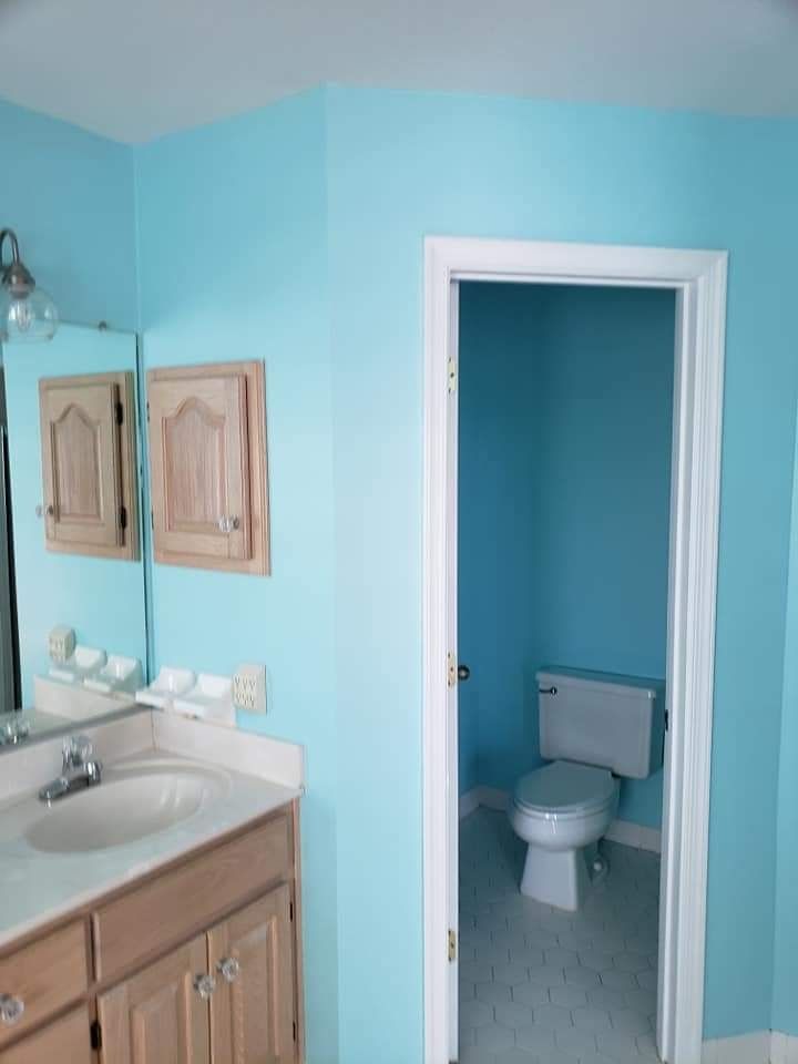 Bathroom with turquoise walls, vanity sink, and open doorway to a small toilet room.
