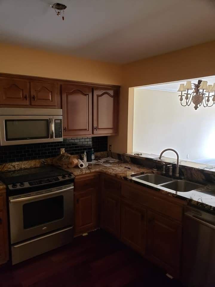 Kitchen with dark wood cabinets, stainless appliances, granite counters, and a large window over the sink.