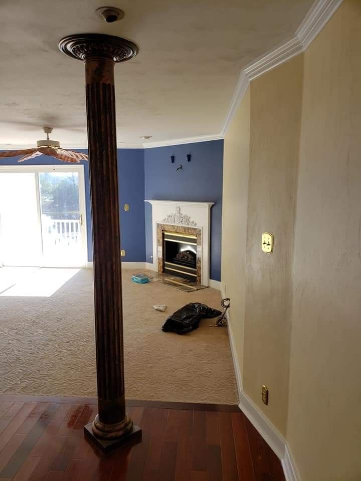 Living room with blue accent wall, fireplace, wooden column, and sliding glass door to outside.