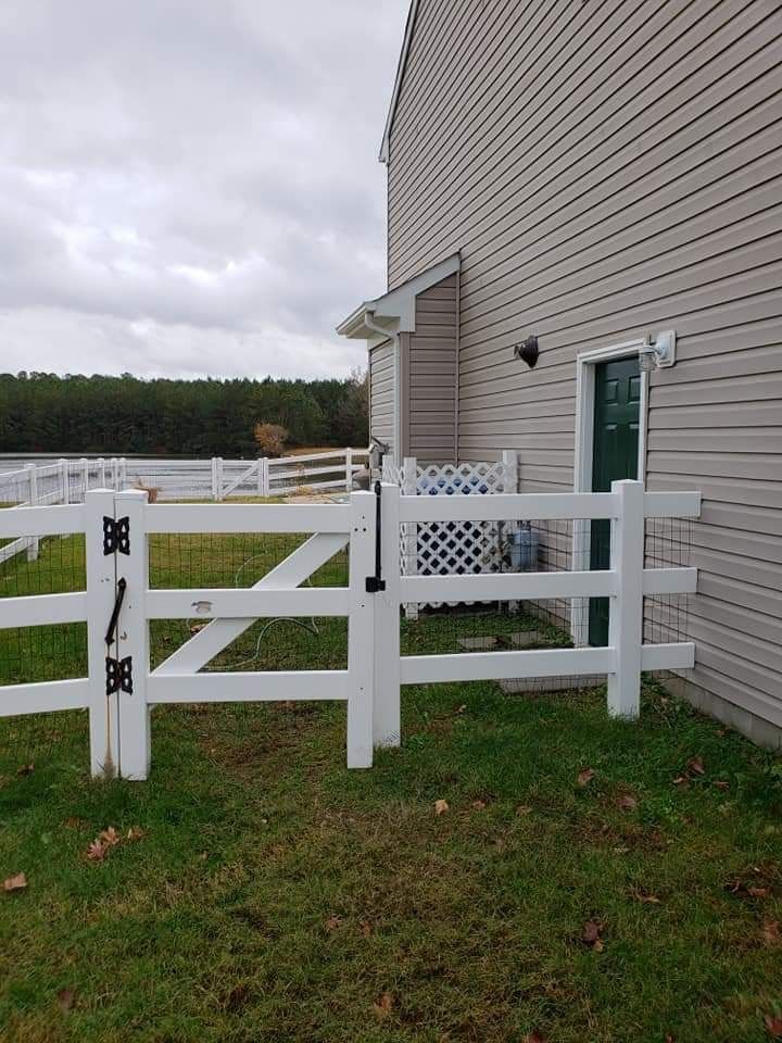 White fence and beige house by a grassy yard under a cloudy sky