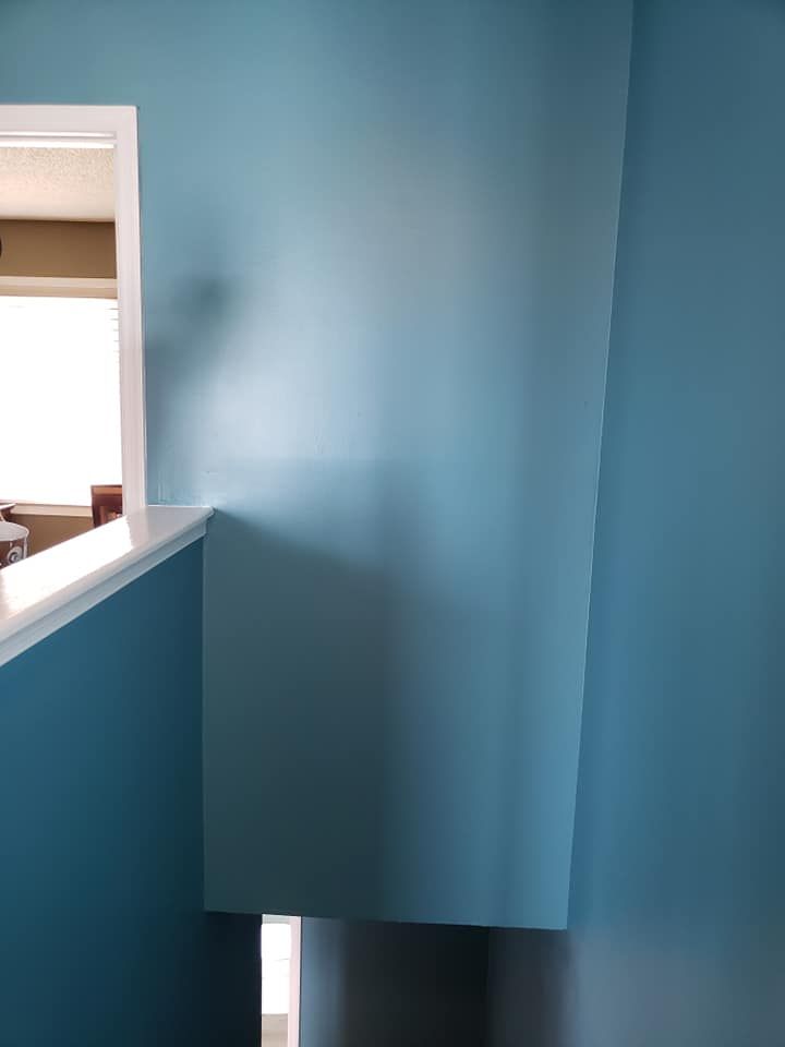 Blue-painted stairwell with a white railing and a doorway opening on the left