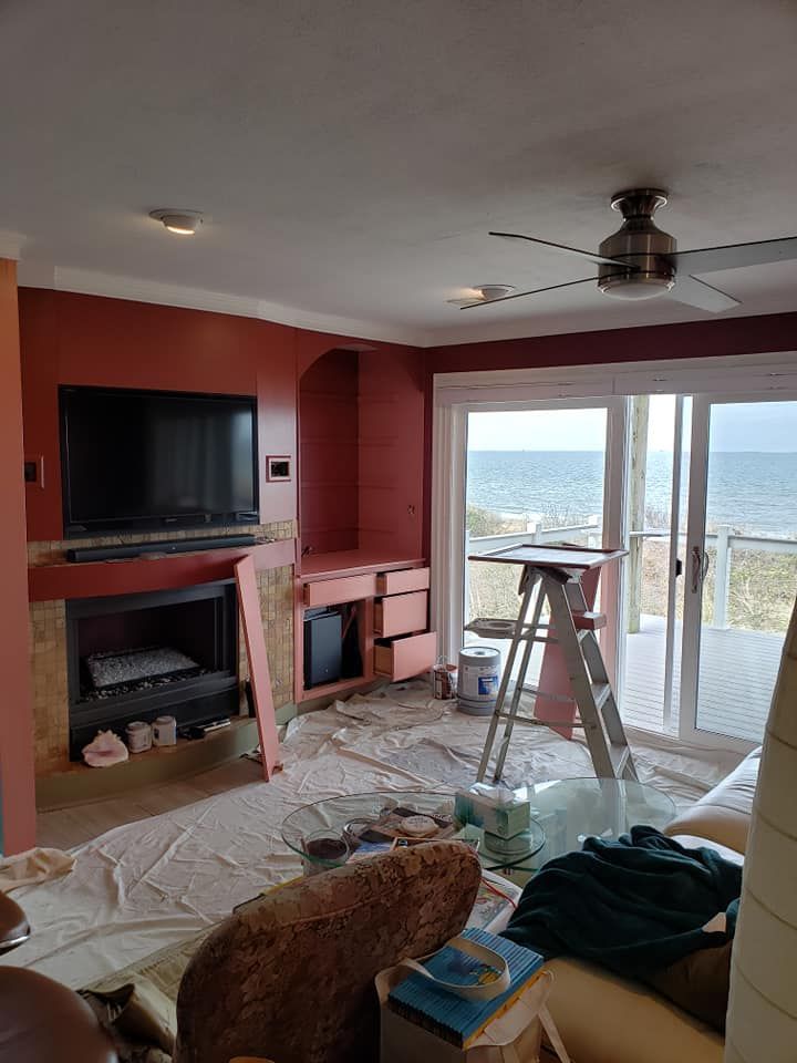 Living room under renovation with TV, fireplace, ladder, and sliding glass doors overlooking mountains