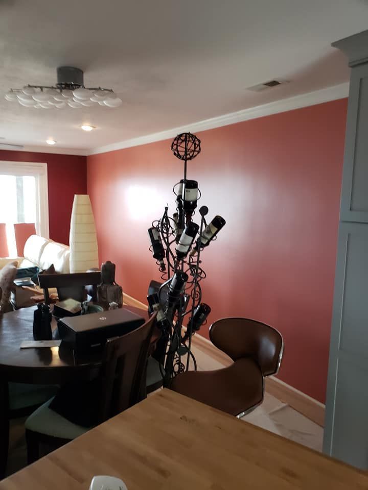 Dining room with coral walls, dark table and chairs, a tall black metal sculpture, and a gray cabinet