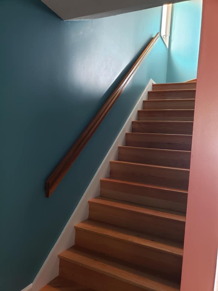 Indoor staircase with brown steps, teal walls, and a wooden handrail.