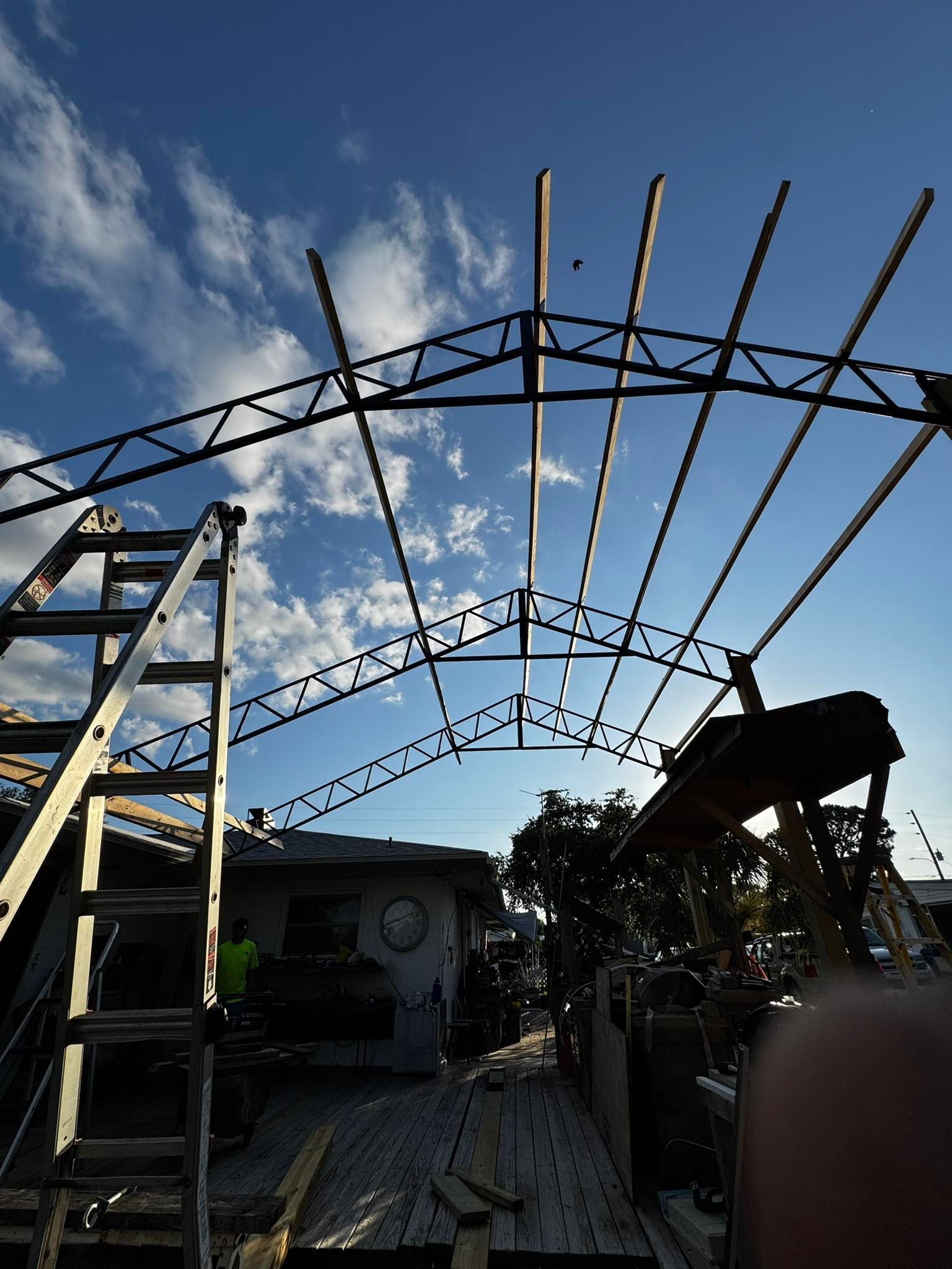 Metal frame of a structure against a blue sky, with a ladder to the side.