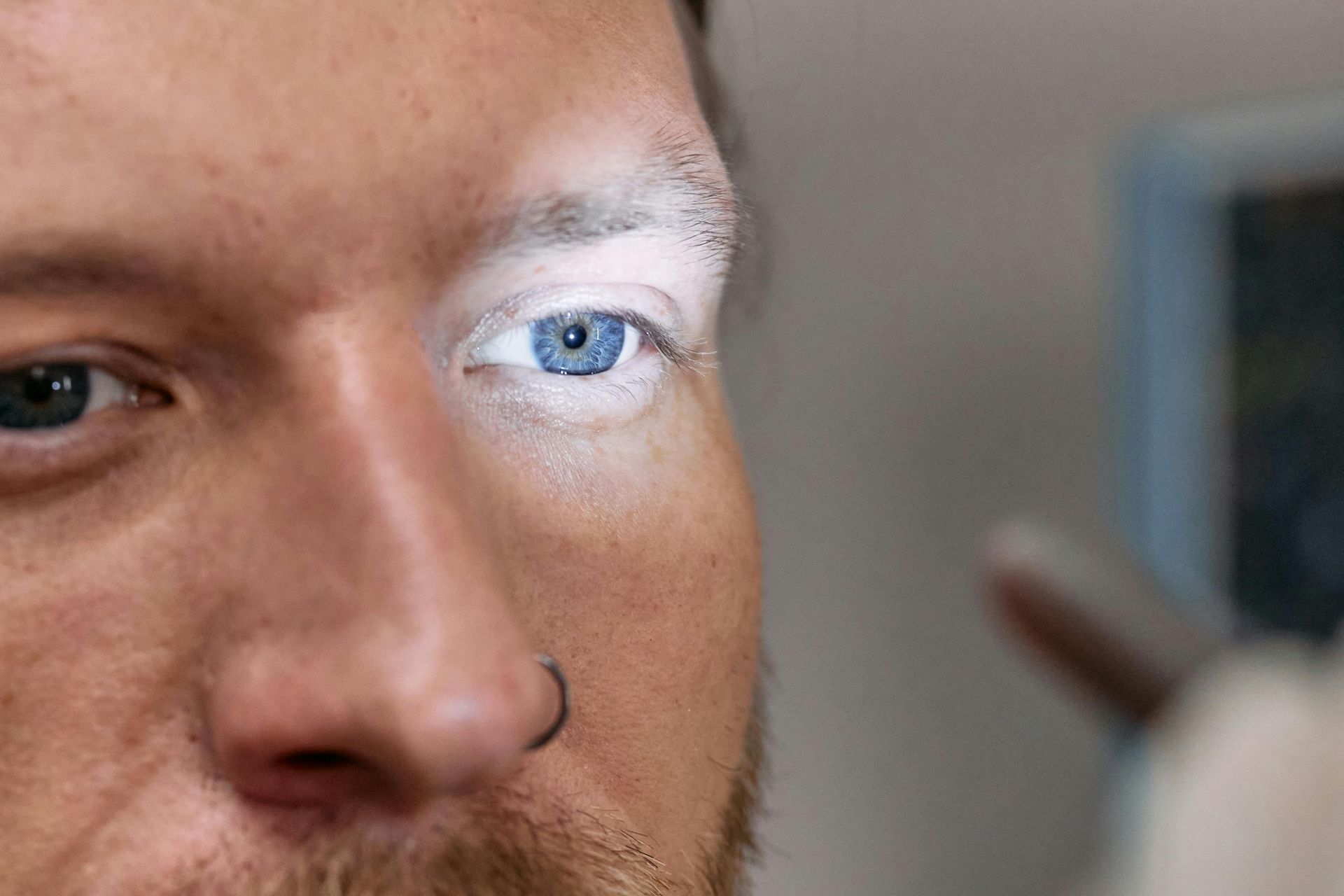 Primer plano de una persona con maquillaje blanco aplicado en el párpado, dejando ver el iris de un azul brillante.