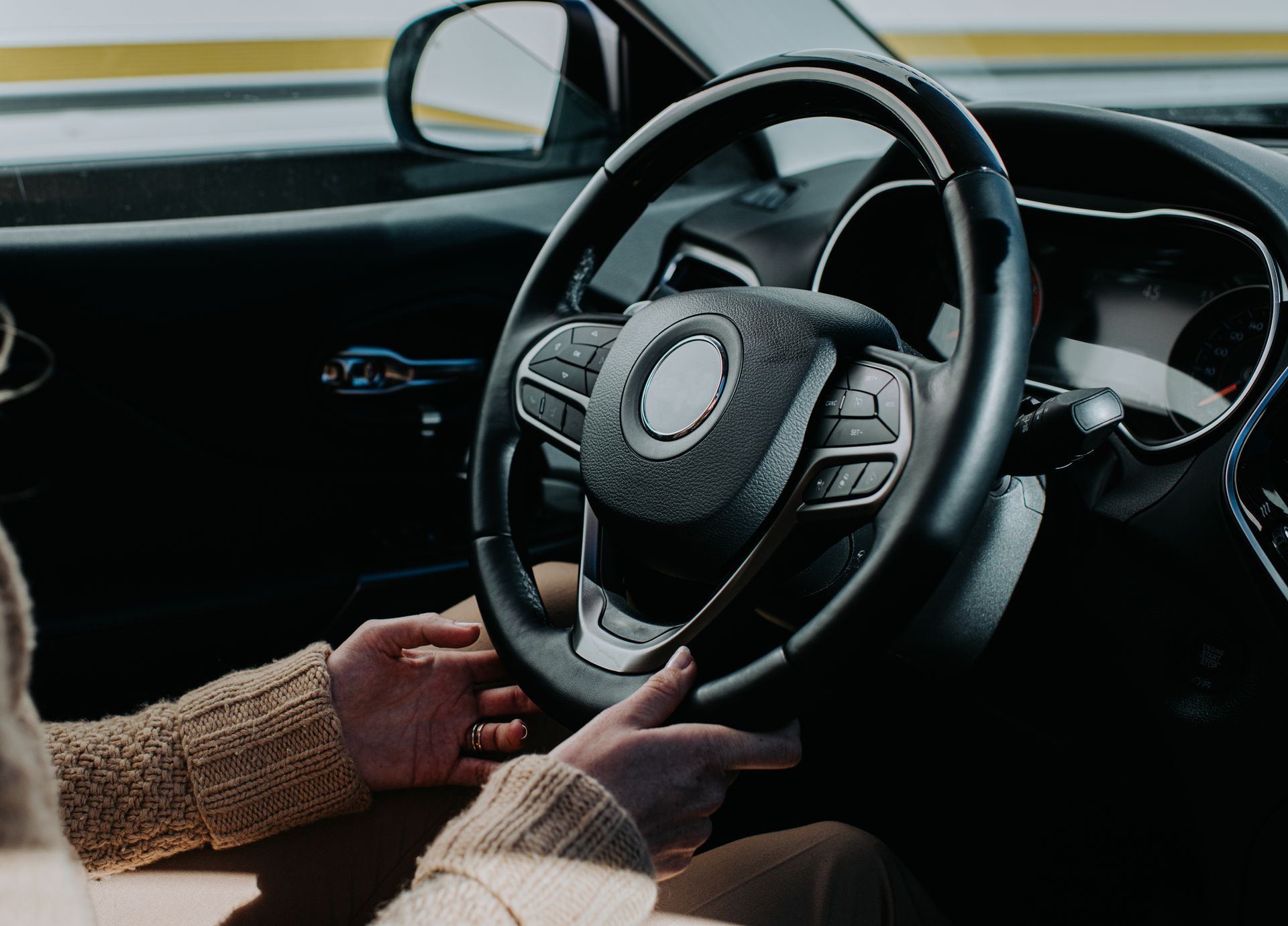 Close-up of female hands holding the steering wheel in a car, highlighting auto insurance coverage.