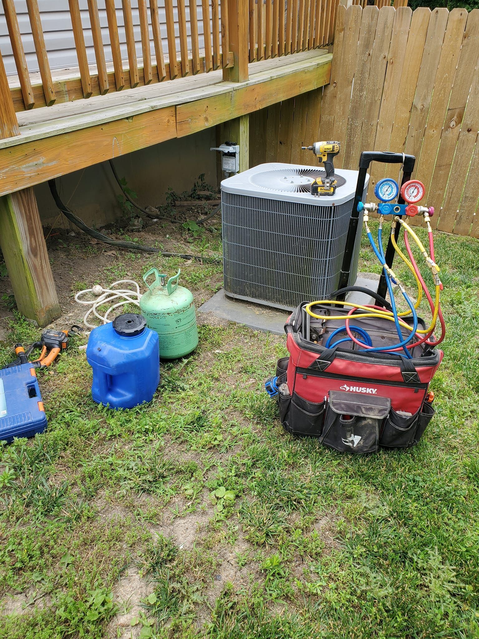 An air conditioner is being repaired in a backyard.