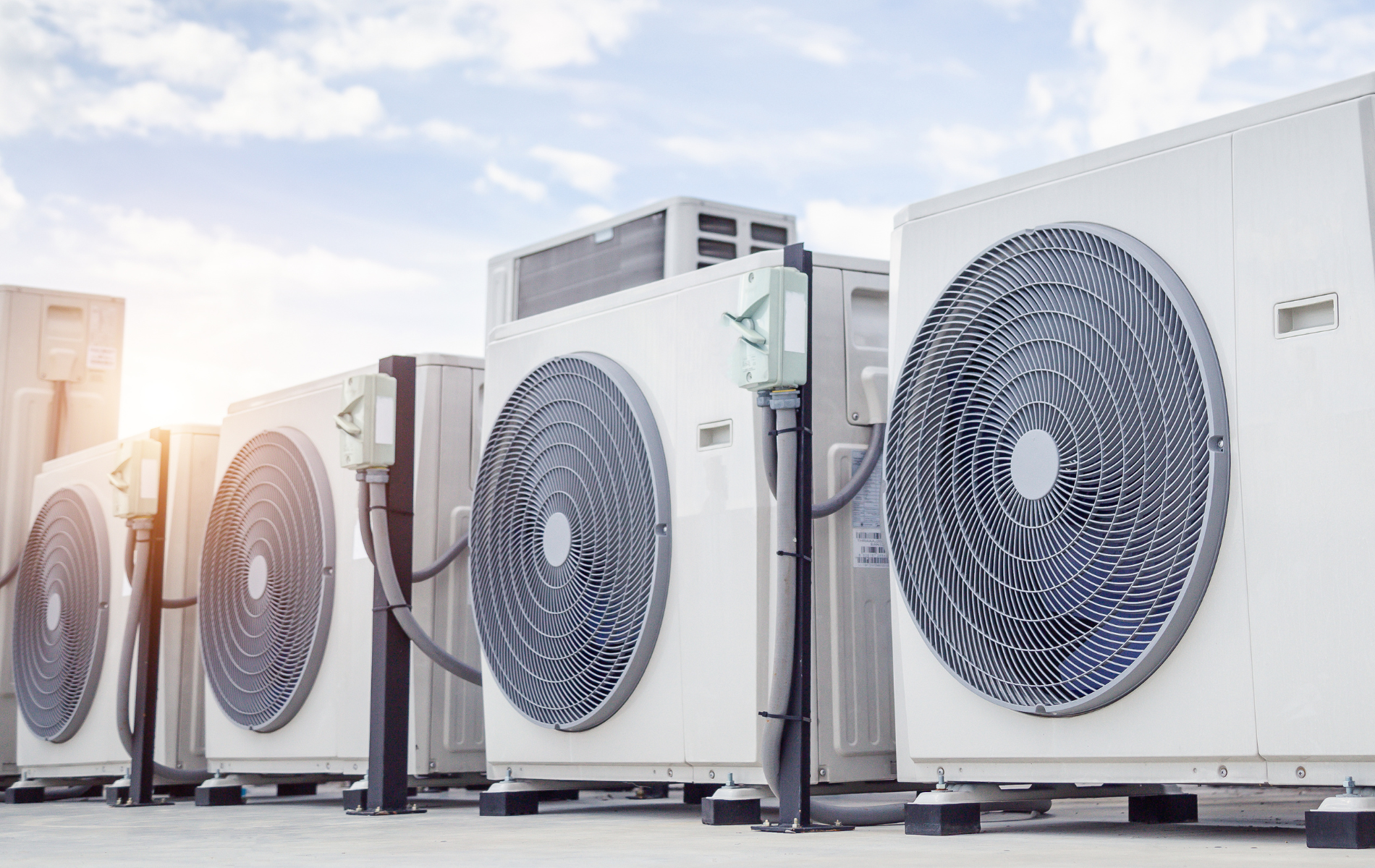 A row of air conditioners sitting on top of a building.
