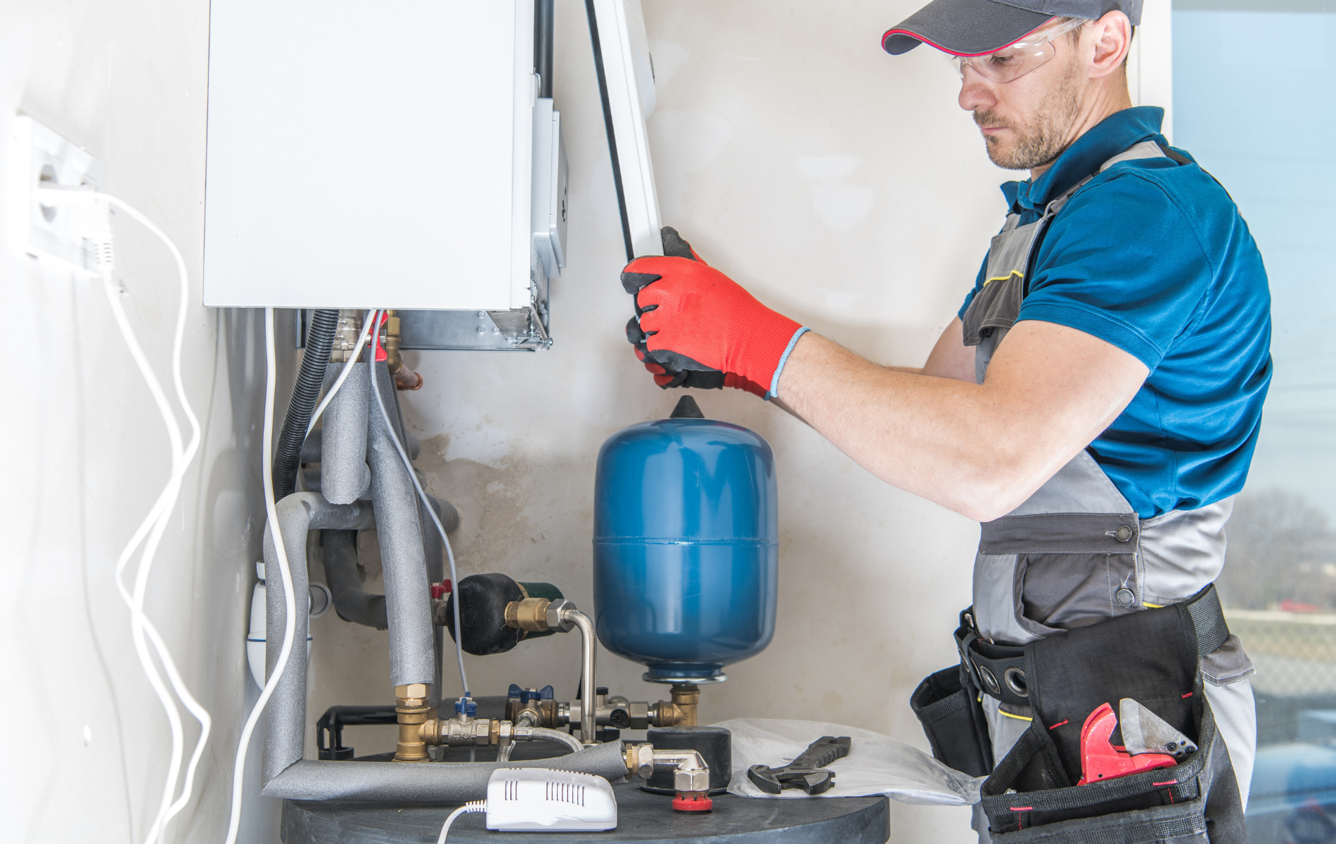 A man is working on a boiler in a room.
