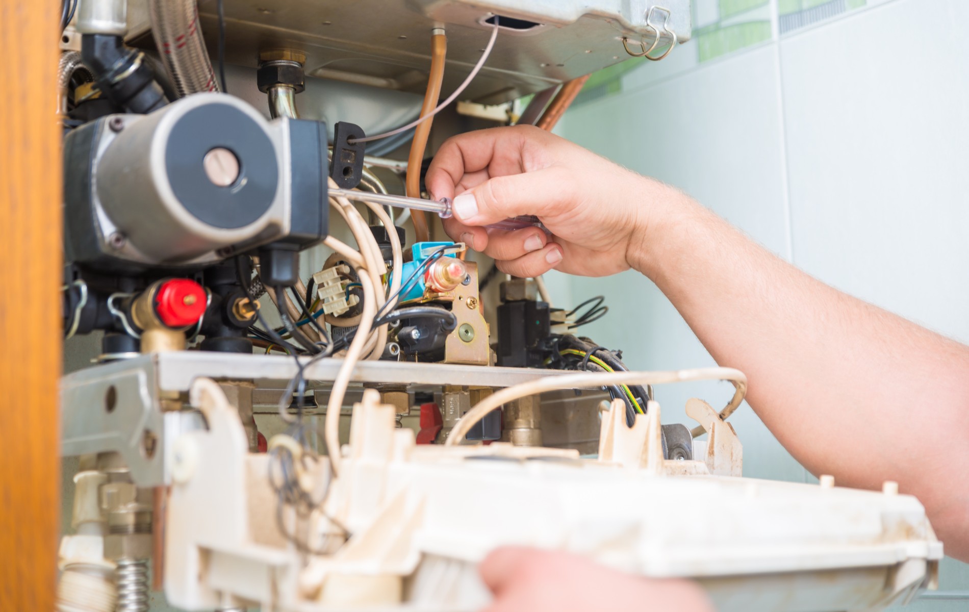 A person is fixing a boiler with a wrench.