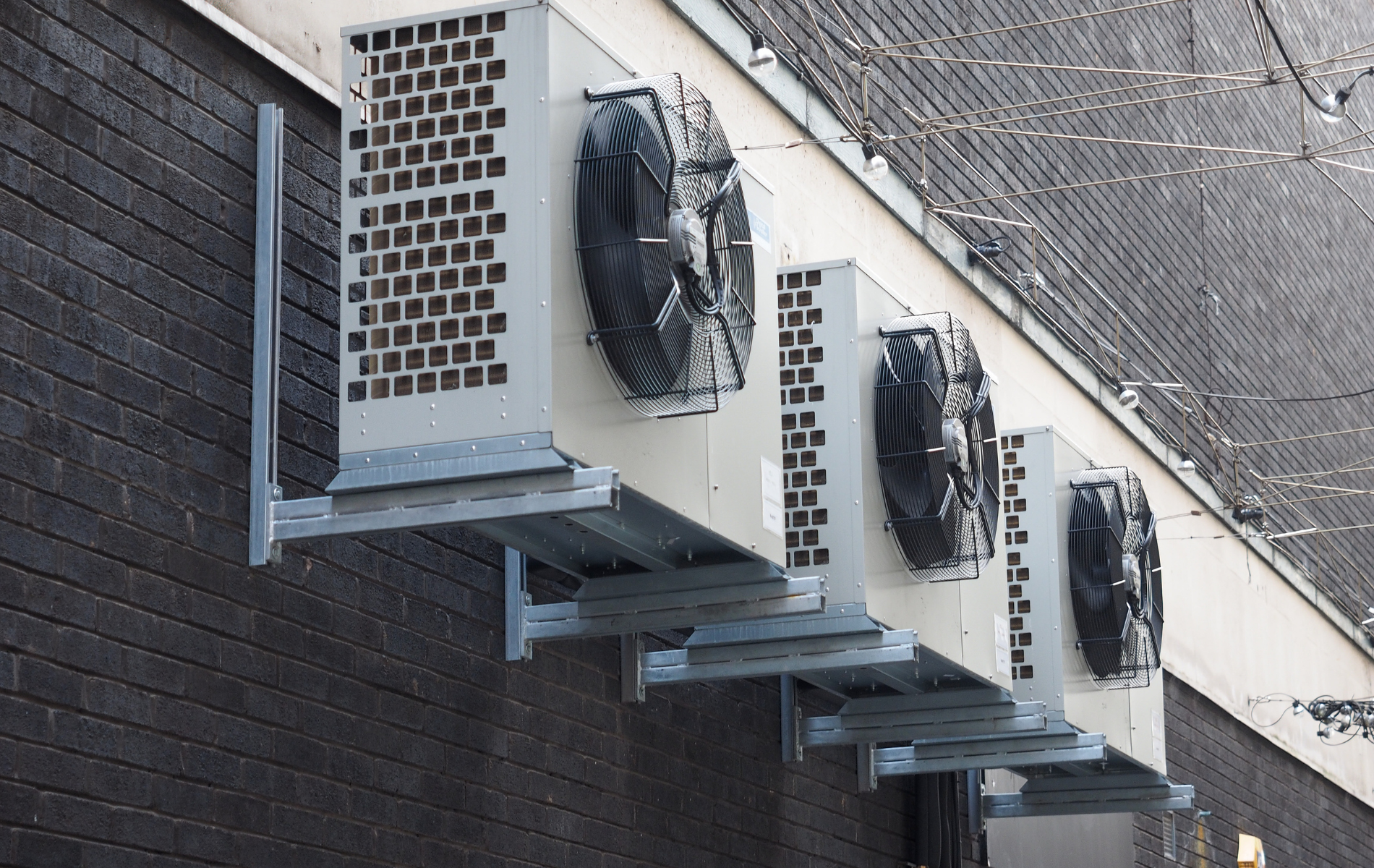 A row of air conditioners are mounted on the side of a building.