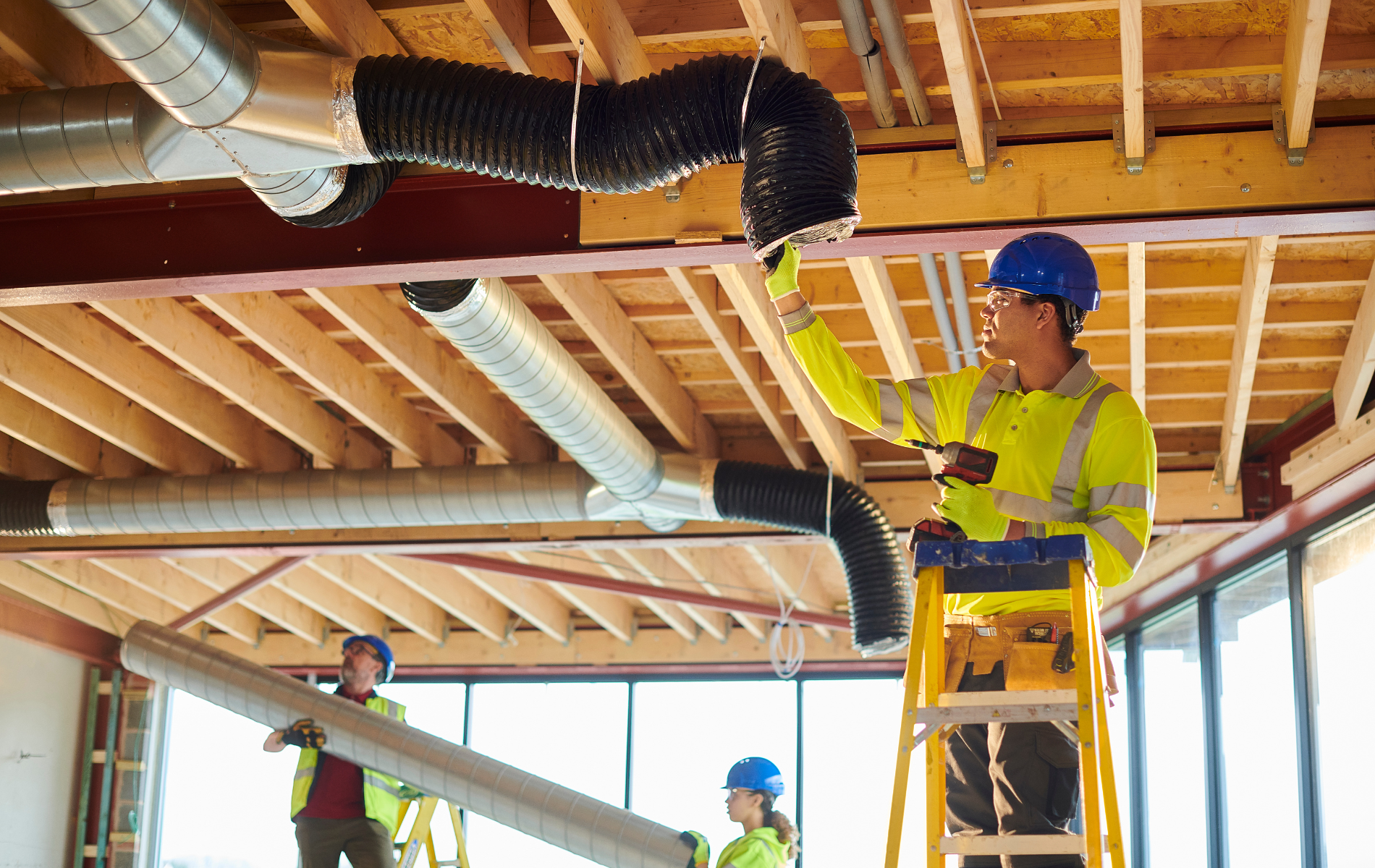 A group of construction workers are working on the ceiling of a building.