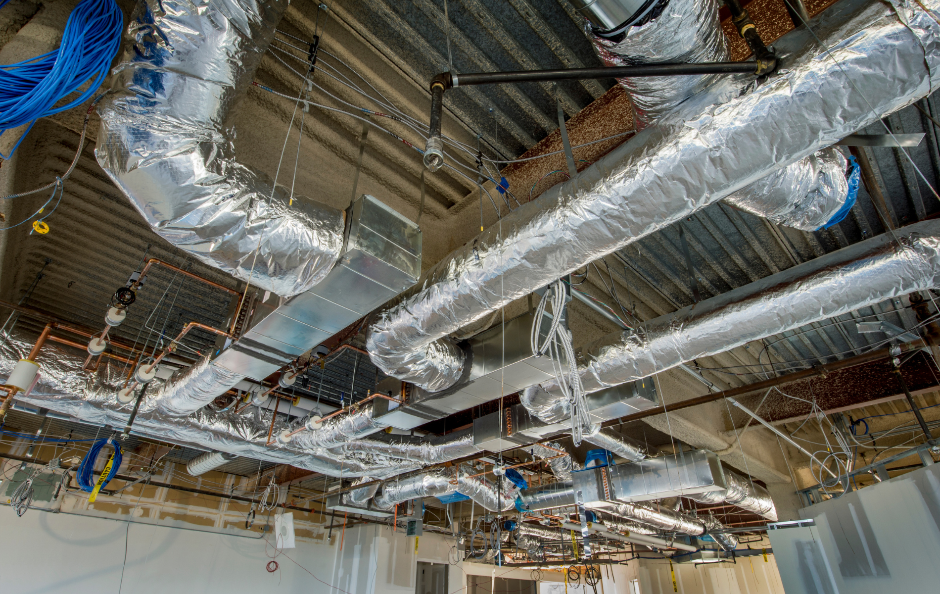 There are a lot of pipes hanging from the ceiling of a building.