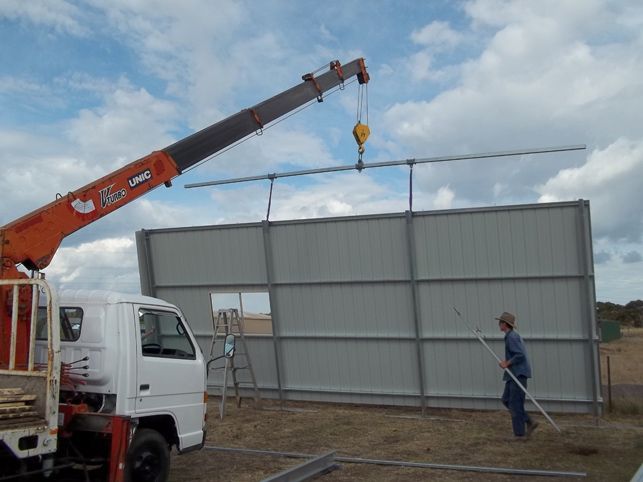 A man is standing in front of a truck with a crane attached to it