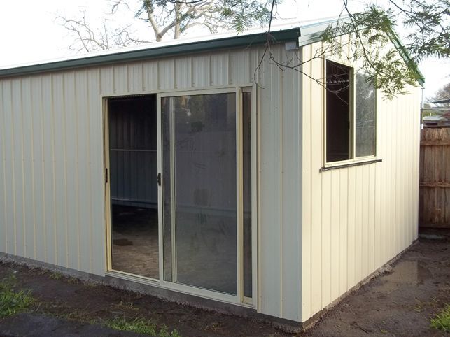 A white shed with a sliding glass door and a window.