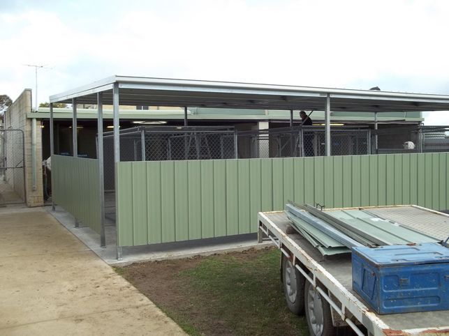 A truck is parked in front of a building with a green fence.
