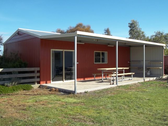 A red house with a covered porch and a picnic table