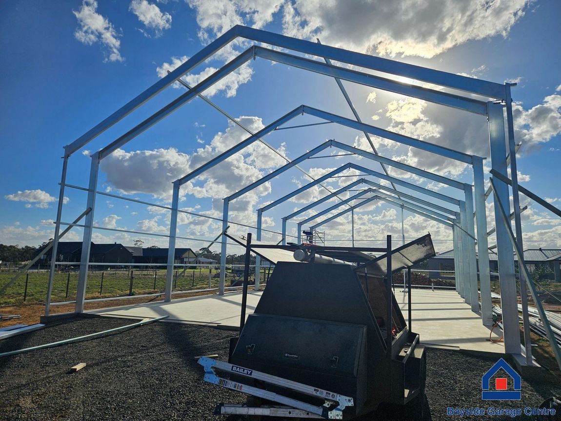 A large metal structure is being built on top of a dirt field.