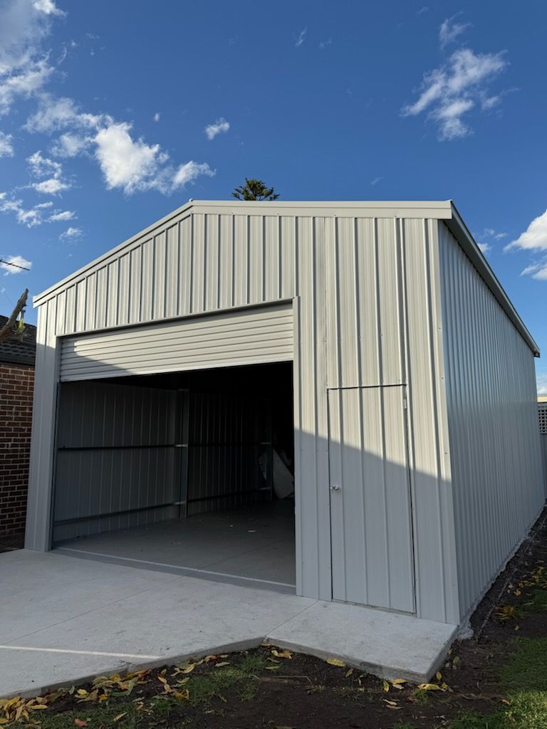A white garage with a roller door and a blue sky in the background.