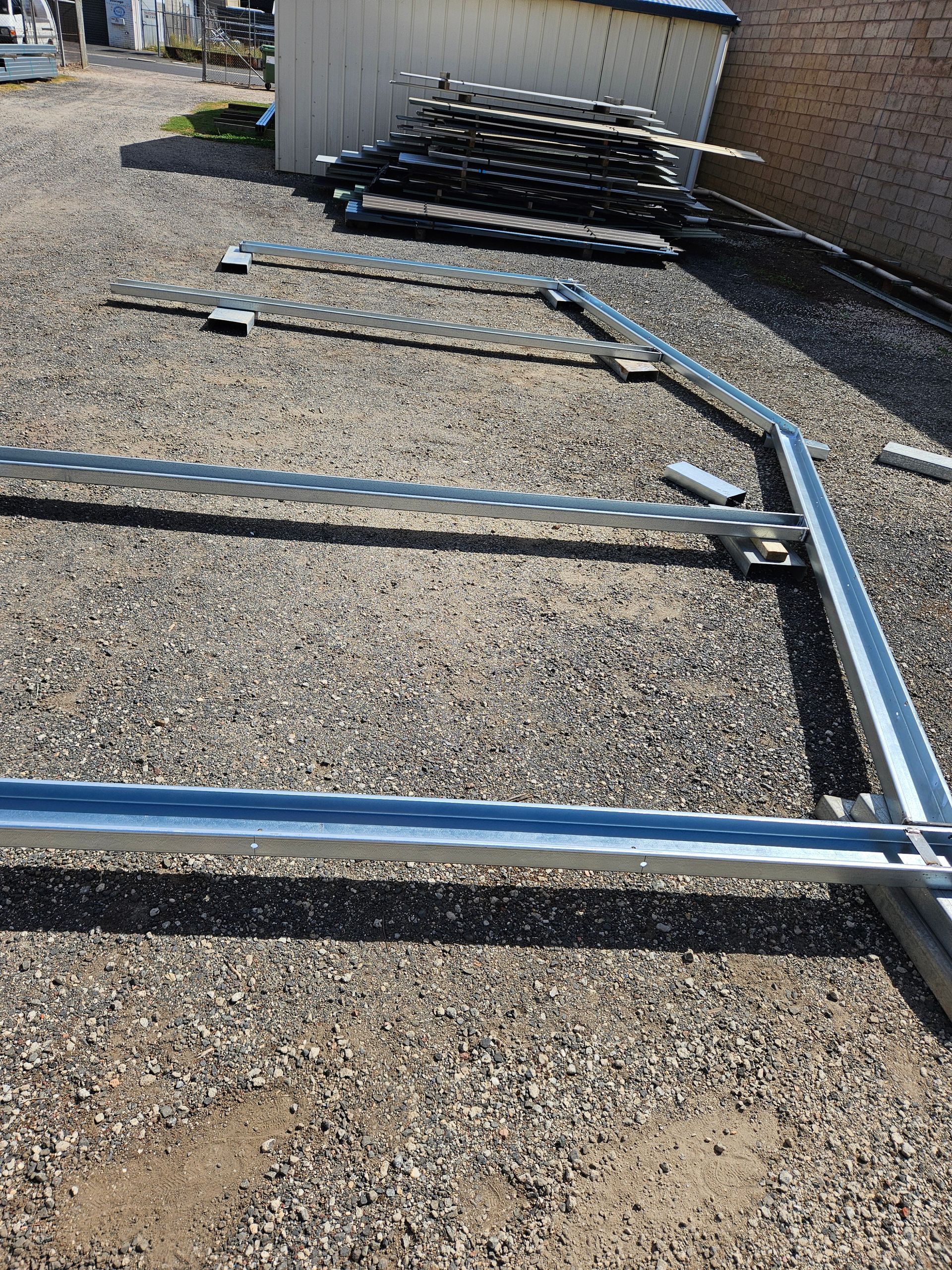 A metal structure is being built in the backyard of a house.